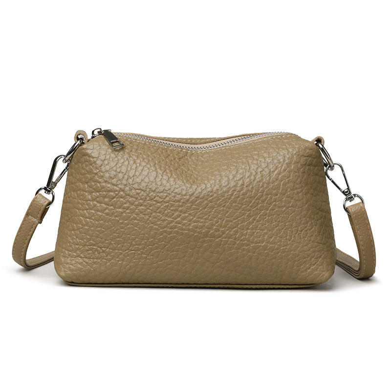 Front view of khaki pebbled cowhide bag with metal strap clips