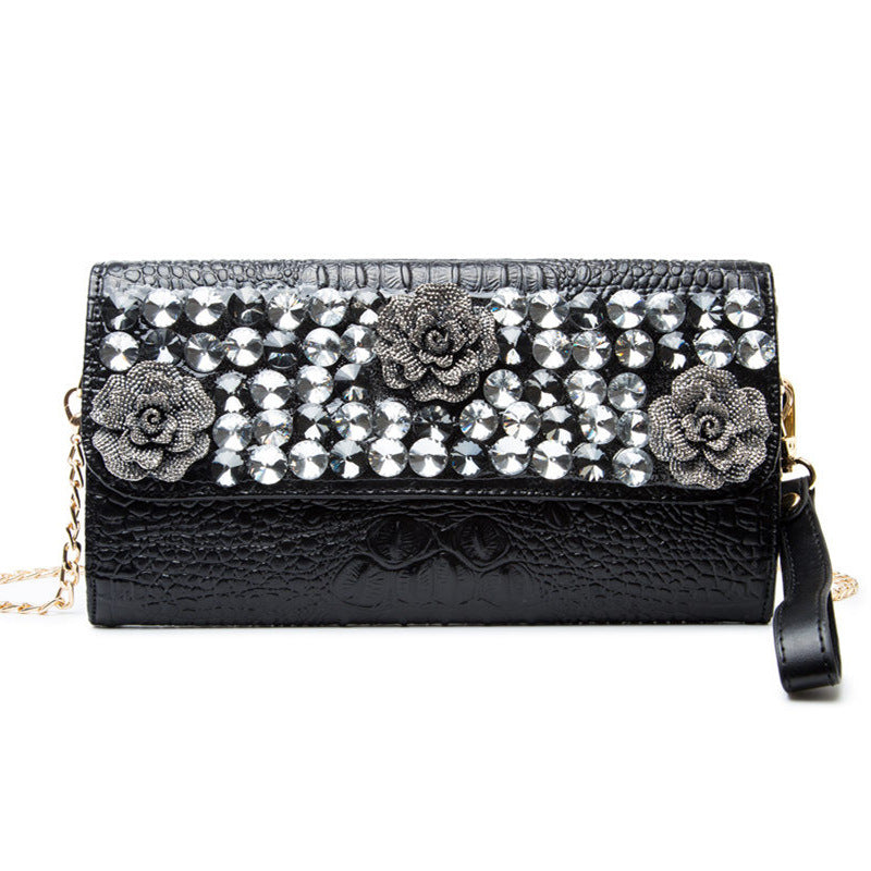 Front view of the black clutch with rose details, crystal-style accents, and chain strap