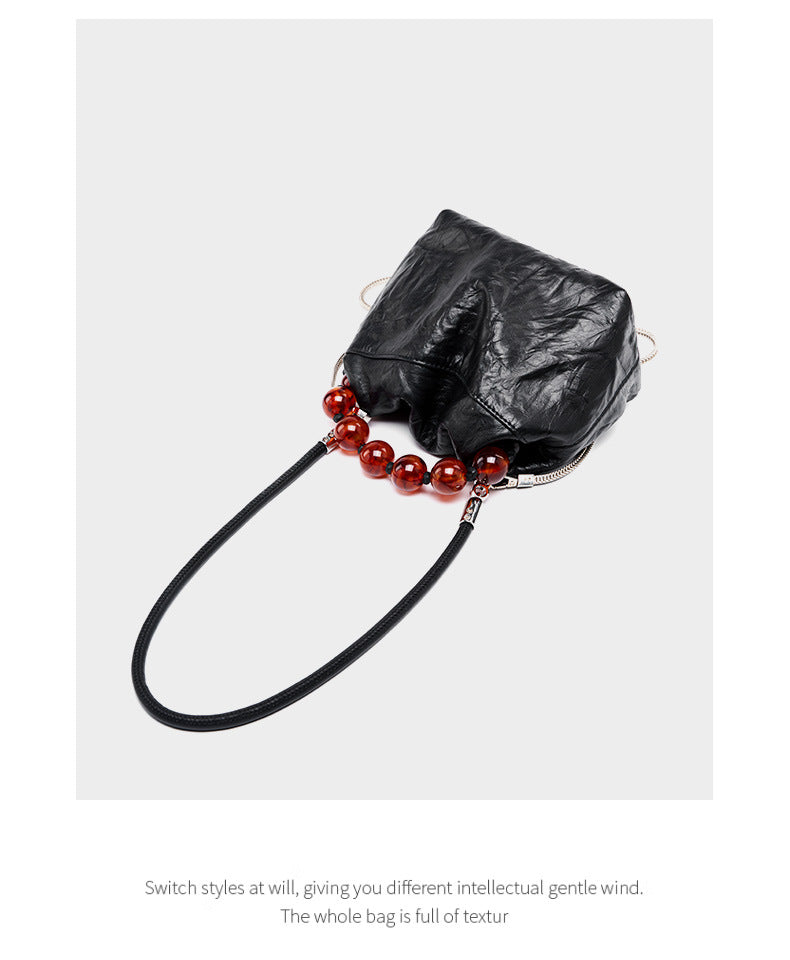 Black crinkle bag laid flat showing bead handle and chain strap detail