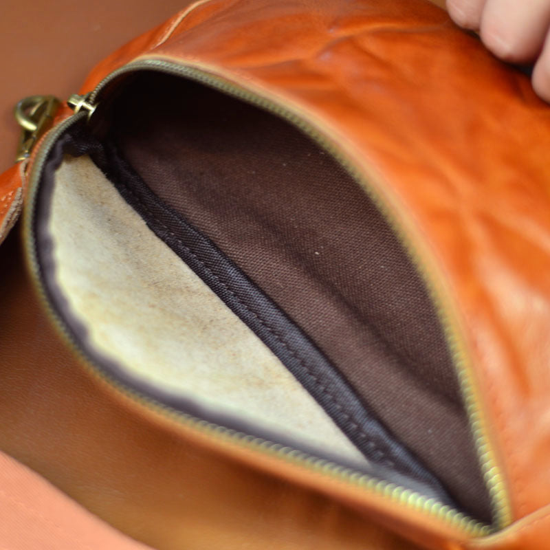 Open brown leather sling bag showing cotton lining and interior phone pocket
