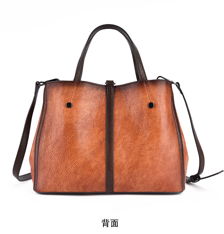 Back view of a brown leather tote with top handles and an adjustable shoulder strap