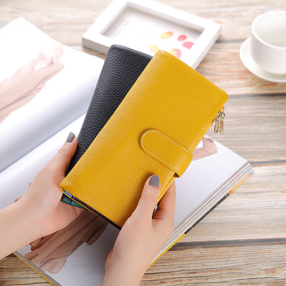 Two-tone yellow and black leather wallets held in hand over an open magazine