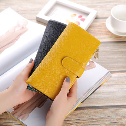 Two-tone yellow and black leather wallets held in hand over an open magazine