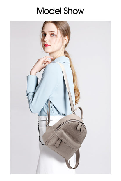 Gray mini backpack shown on a model at the shoulder