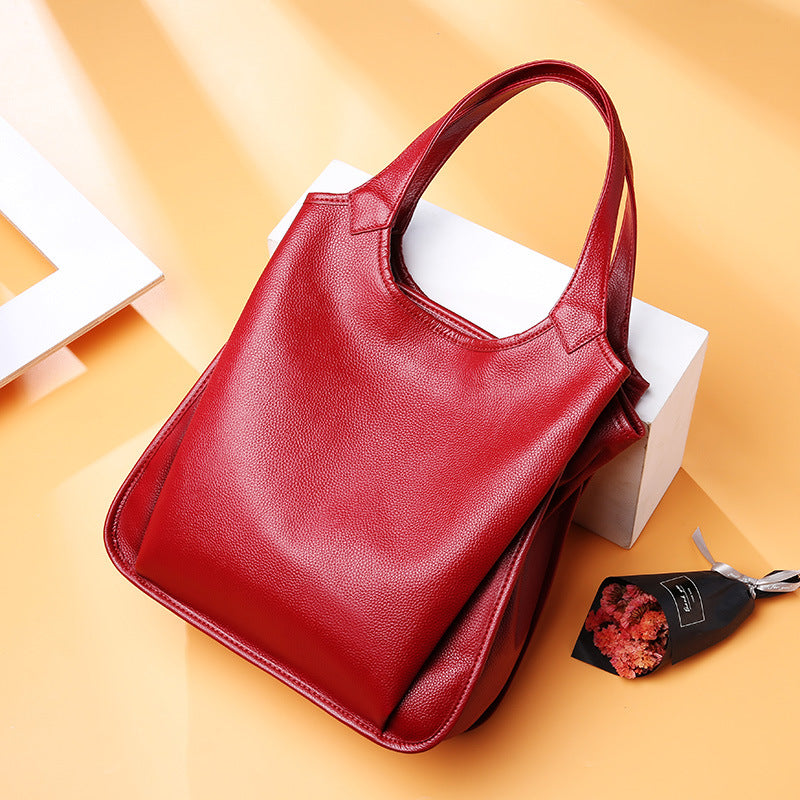 Wine red pebbled leather tote bag styled on a peach background