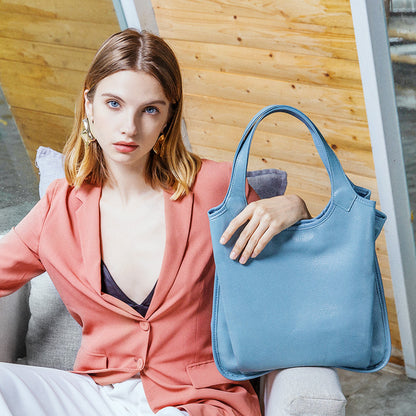 Woman in coral blazer holding a light blue leather tote bag