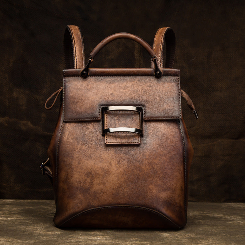 Coffee brown leather backpack with a structured silhouette and metal front accent