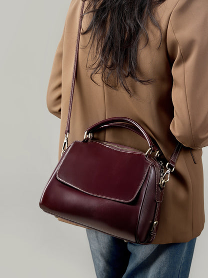 Wine brown Boston bag worn crossbody with model in camel coat