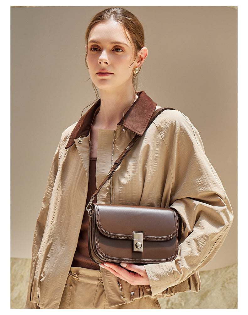 Brown leather messenger bag held at waist with crossbody strap