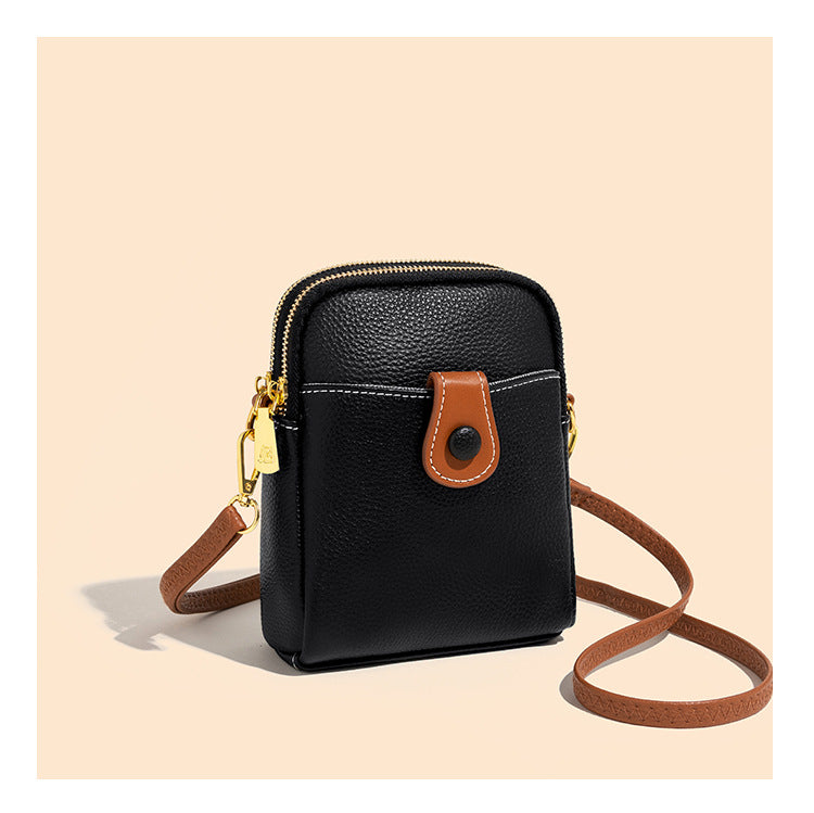 Side angle of black pebbled cowhide bag with brown contrast strap loop and gold clips