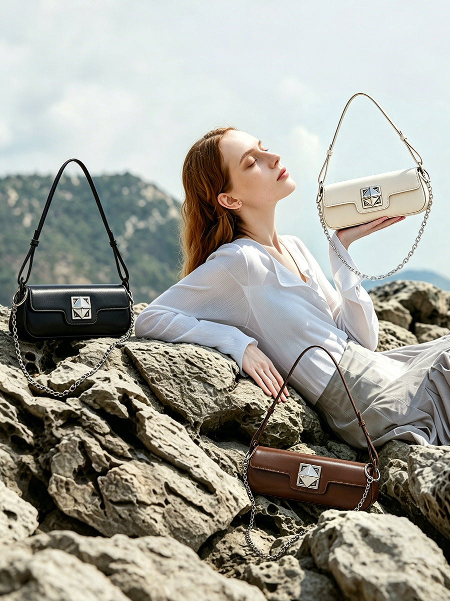Multiple leather baguette bags in black, caramel, and off-white displayed on rocks