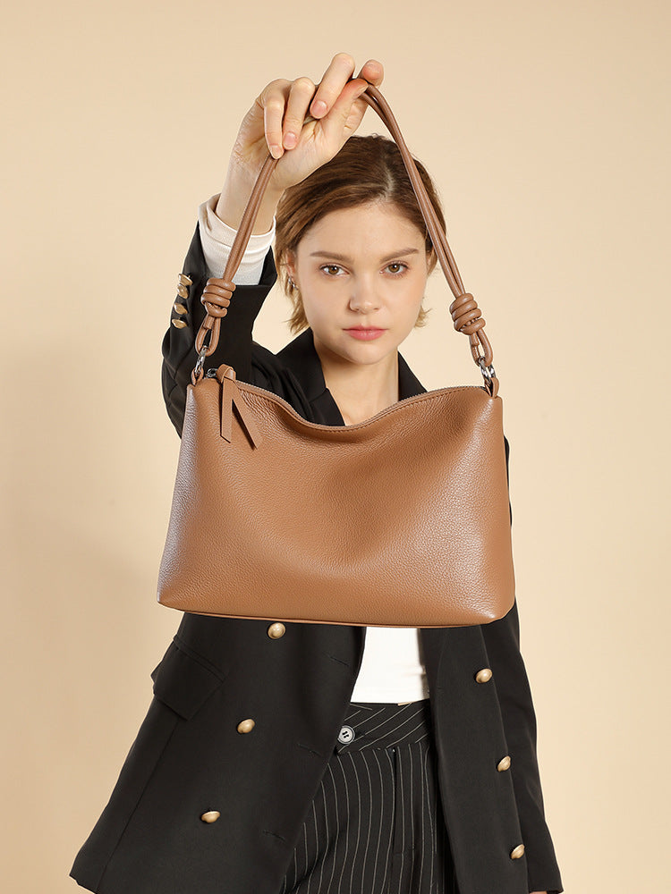 Model holding caramel pebbled cowhide tote under her arm in studio shot