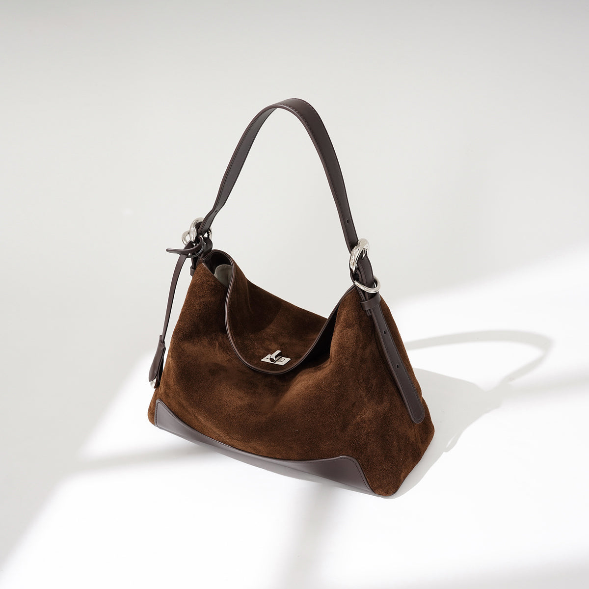 Angled view of the brown tote with curved opening and clasp