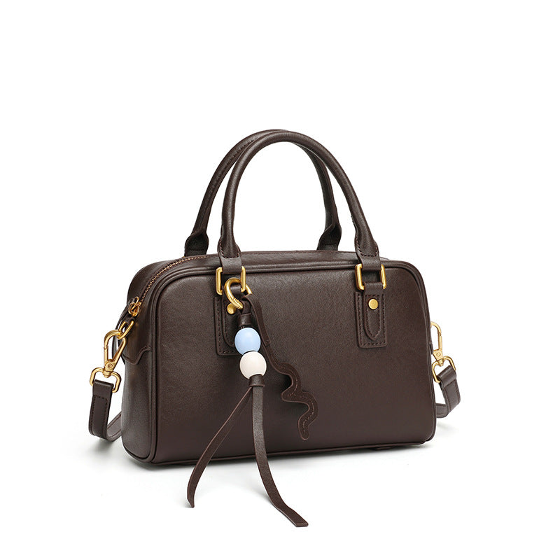 Coffee brown cowhide leather pillow bag with double top handles on a white background