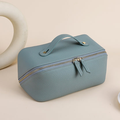 Blue cowhide toiletry pouch showing its top handle and twin zipper pulls