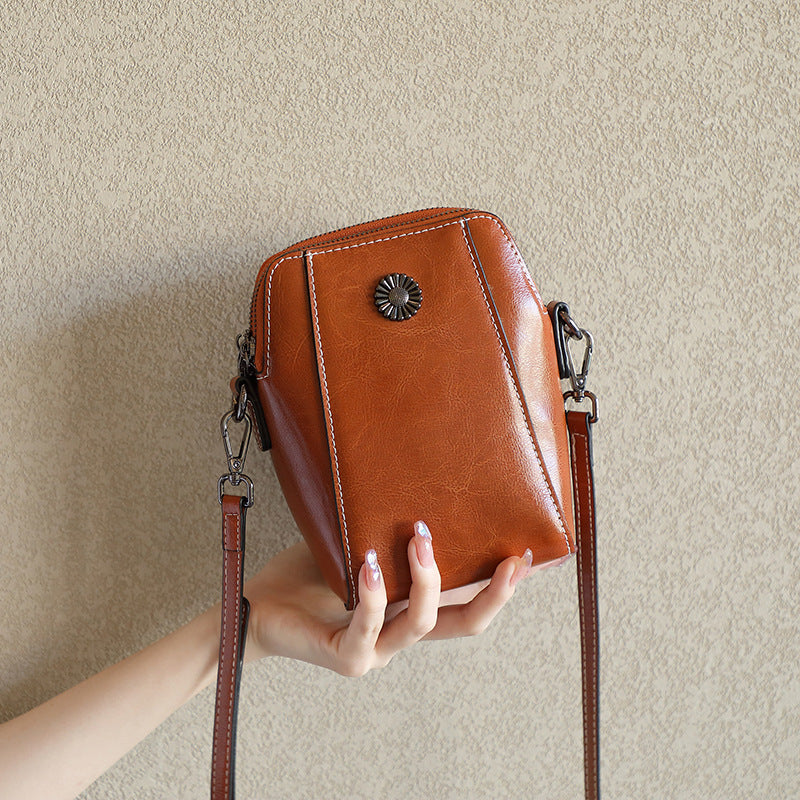 Brown cowhide leather mini crossbody phone bag shown in hand