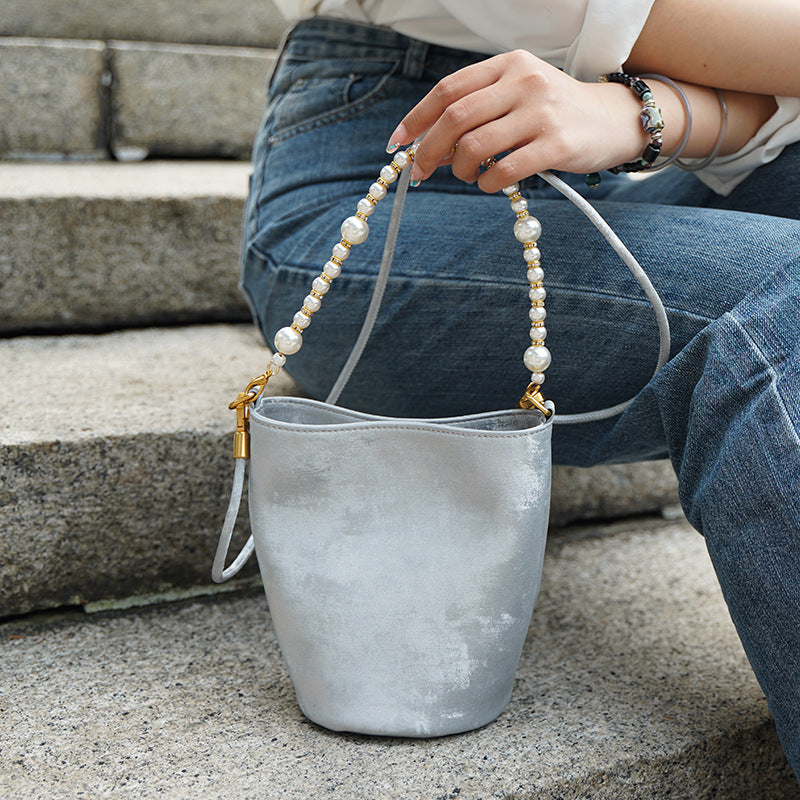 Silver gray mini bucket bag held by hand with pearl chain detail