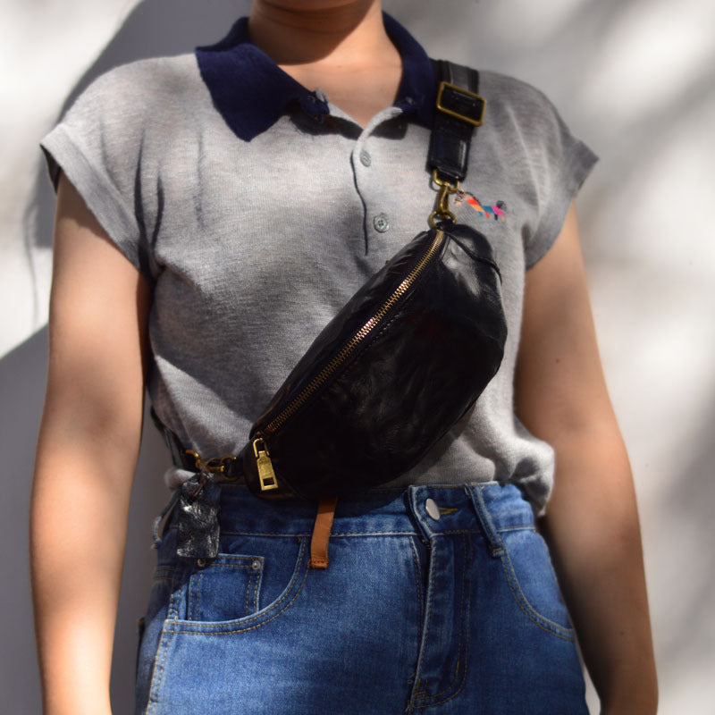 Black leather sling bag worn crossbody across the front