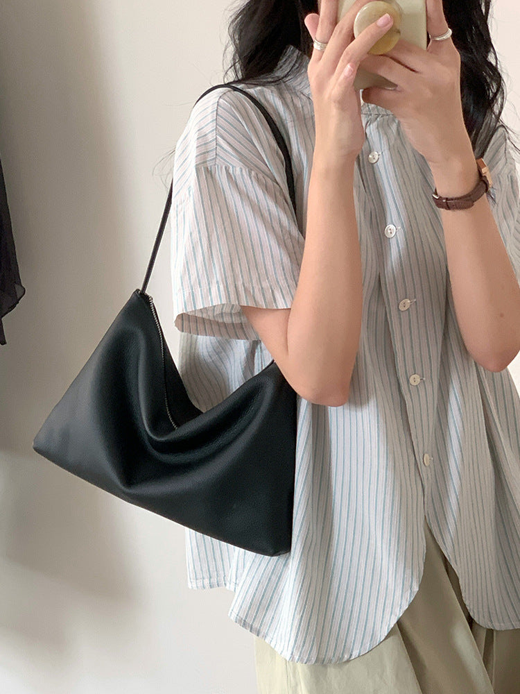 Black hobo shoulder bag carried with a striped shirt