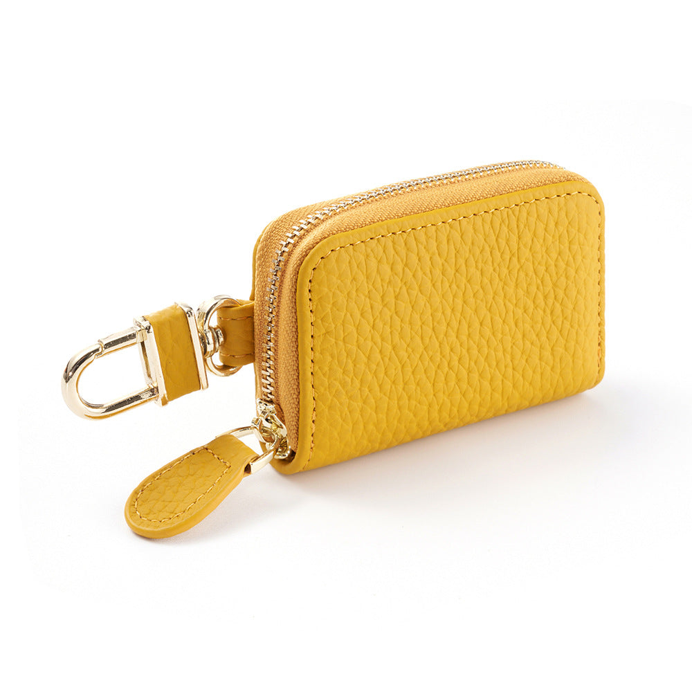 Yellow cowhide leather key case pouch with single zipper and gold-tone rotating clip on white background