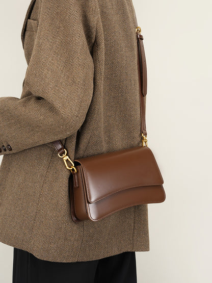 Model wearing brown leather mini bag as shoulder bag with herringbone blazer