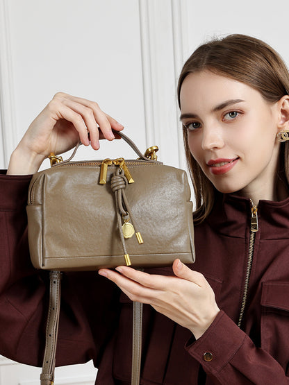 Gray cowhide leather bag held by model showing scale and styling
