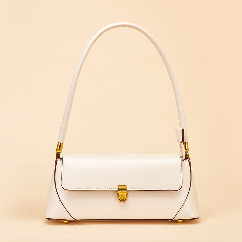 White cowhide baguette shoulder bag with antique brass lock on neutral background
