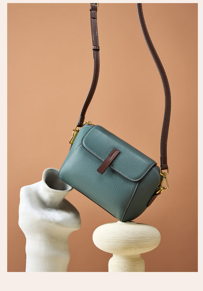 Sea blue shell crossbody bag suspended by strap against a warm beige backdrop