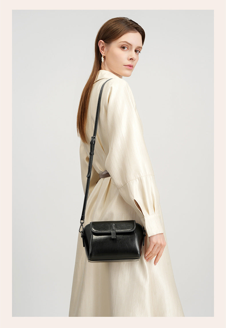 Side view of model carrying a black crossbody bag with adjustable strap