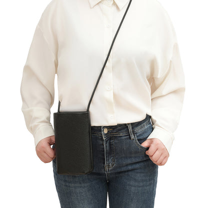 Black leather phone bag worn crossbody with cream blouse and denim jeans