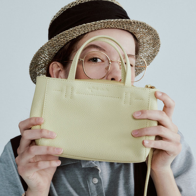 Model holding the small tote to show its compact proportions