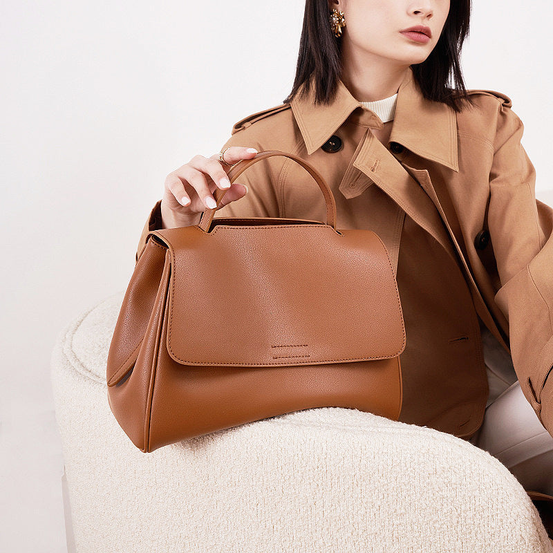 Brown cowhide leather top-handle bag styled with trench coat