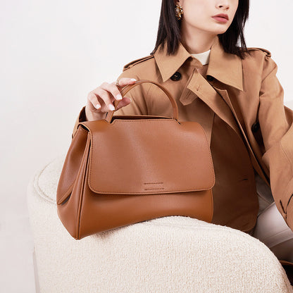Brown cowhide leather top-handle bag styled with trench coat