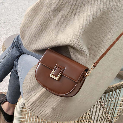 Brown saddle bag worn crossbody over a knit sweater