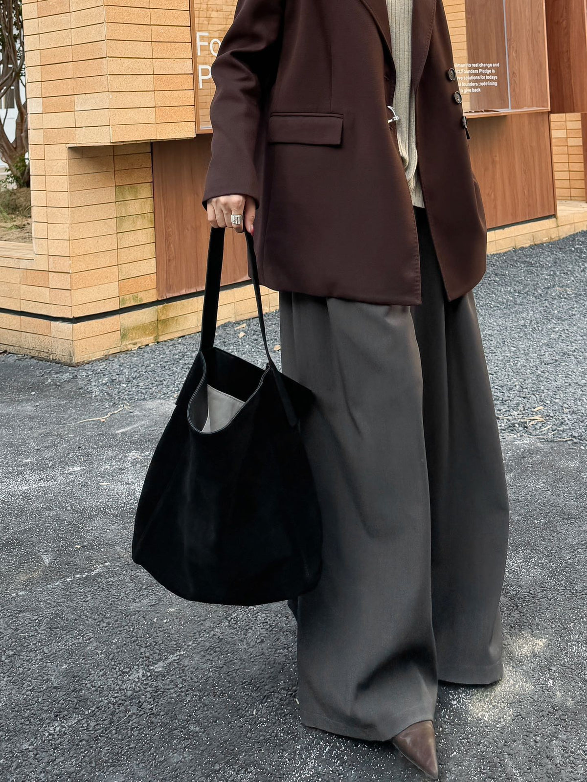 Black tote carried at the side in an outdoor outfit