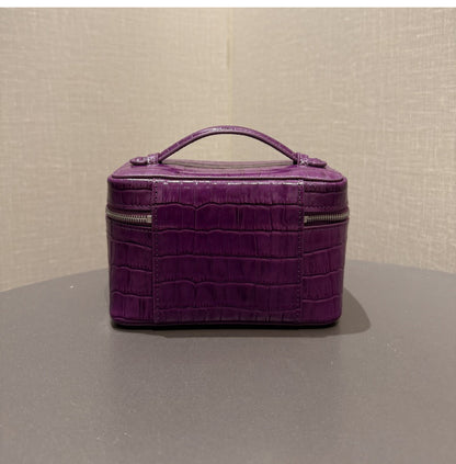 Angled side view of the purple leather cosmetic pouch
