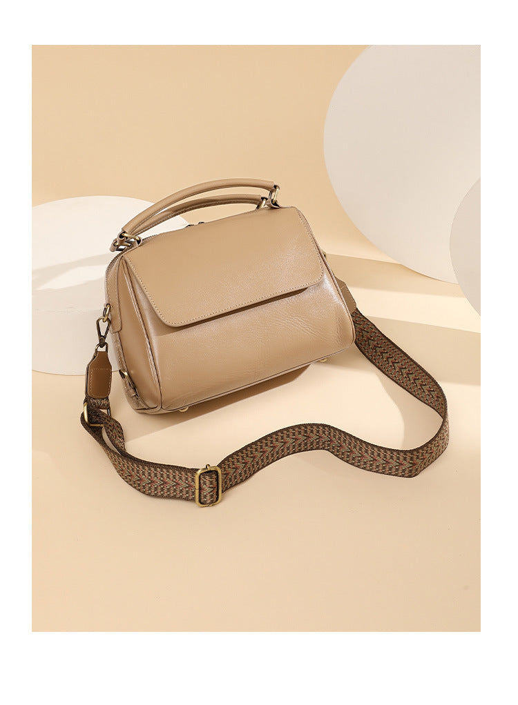 Apricot leather Boston bag with woven shoulder strap on beige background