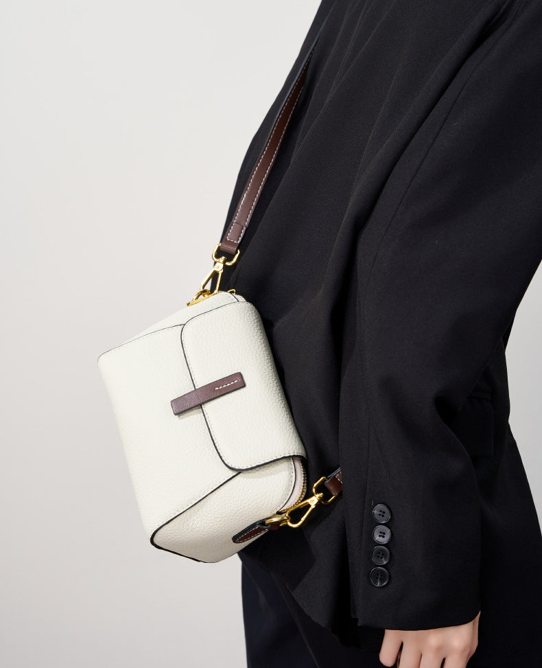 Ivory shell crossbody bag worn crossbody with the strap fully visible against a black blazer