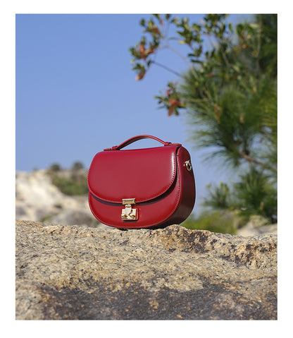 Red saddle bag displayed on a stone with greenery and sky