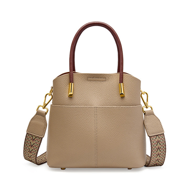 Gray cowhide leather bucket bag with top handles and woven strap on white background