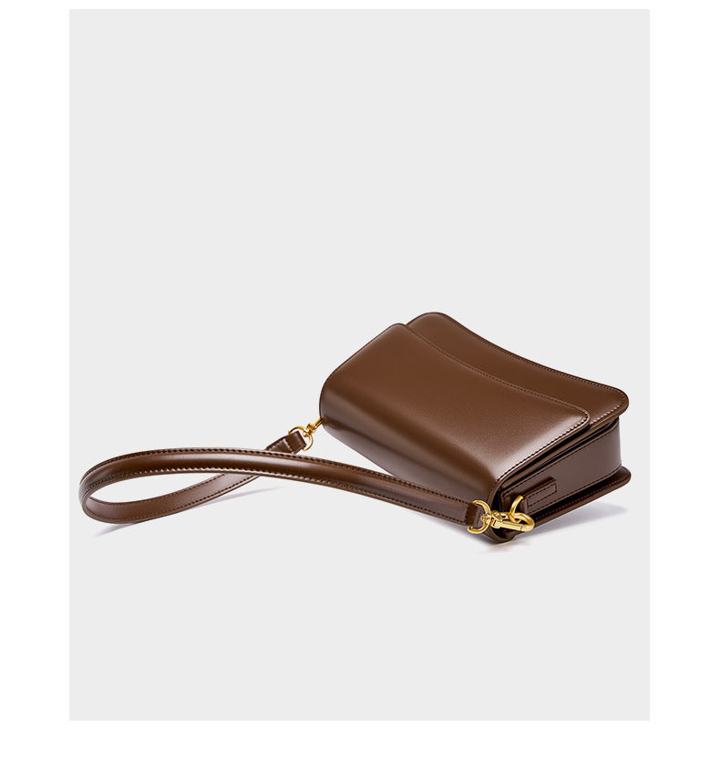 Angled product shot of brown leather bag showing detachable strap and gold hardware