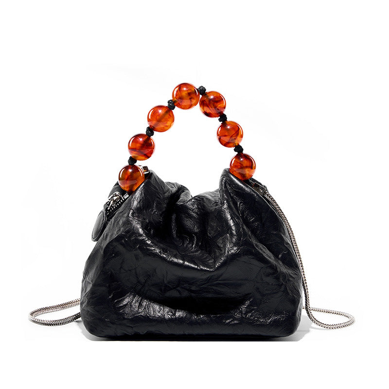 Black crinkle cowhide crossbody bag with amber bead handle on white background