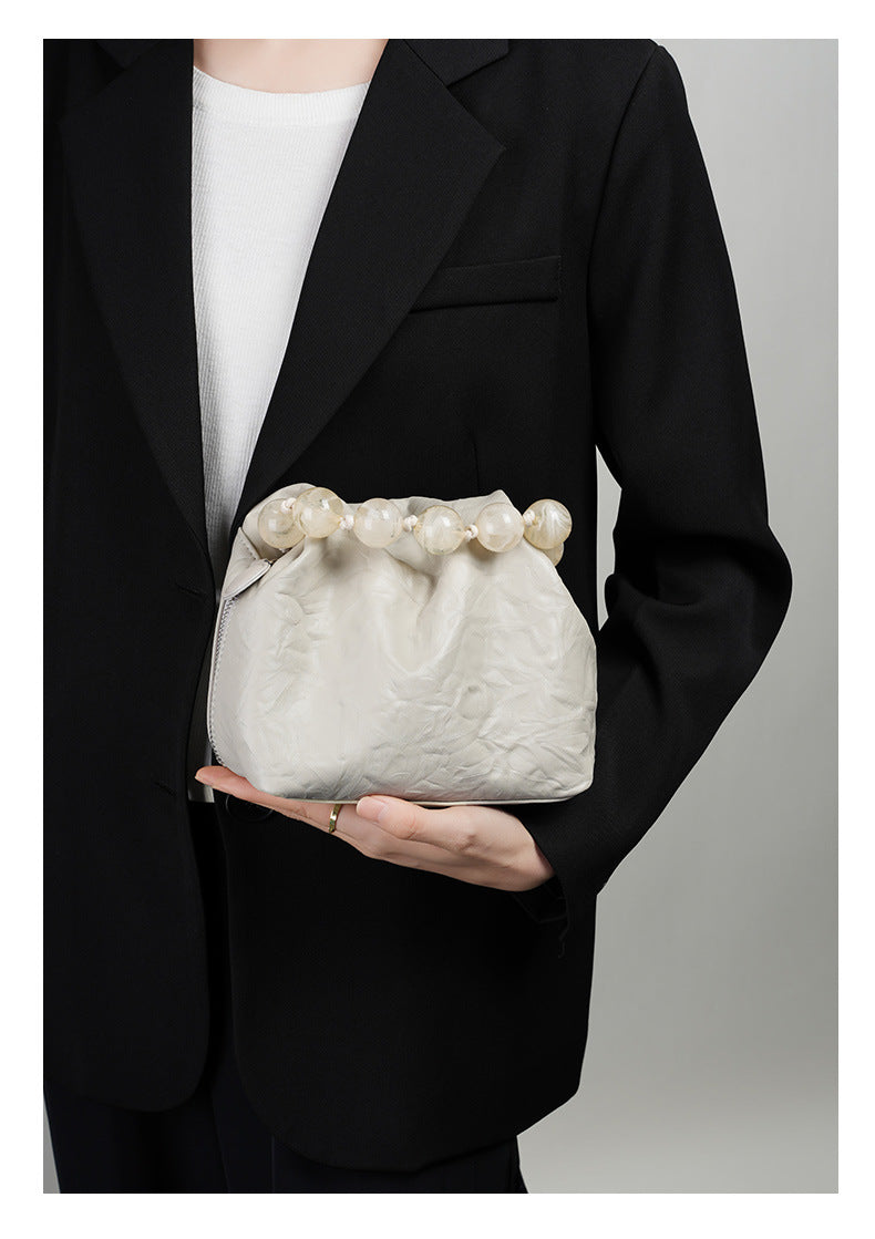 Model holding the off-white crinkle bag in hand against a black blazer