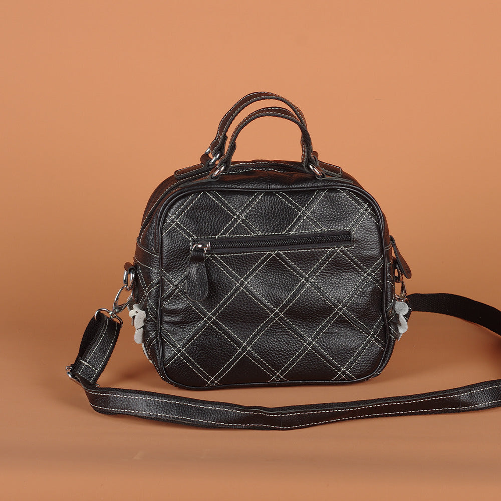Side detail of black cowhide bag with floral appliques and strap hardware