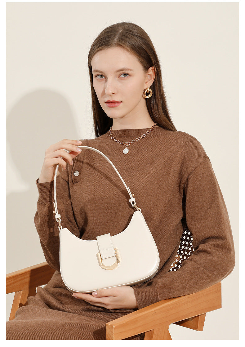 Seated model holding cream white leather shoulder bag