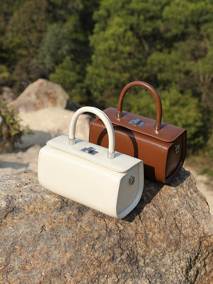 Cream and coffee brown box handbags displayed together on a stone surface
