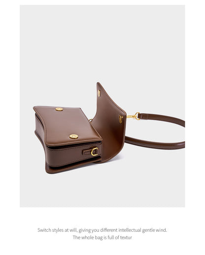 Open flap view of brown leather bag revealing interior pocket and gold-tone rings