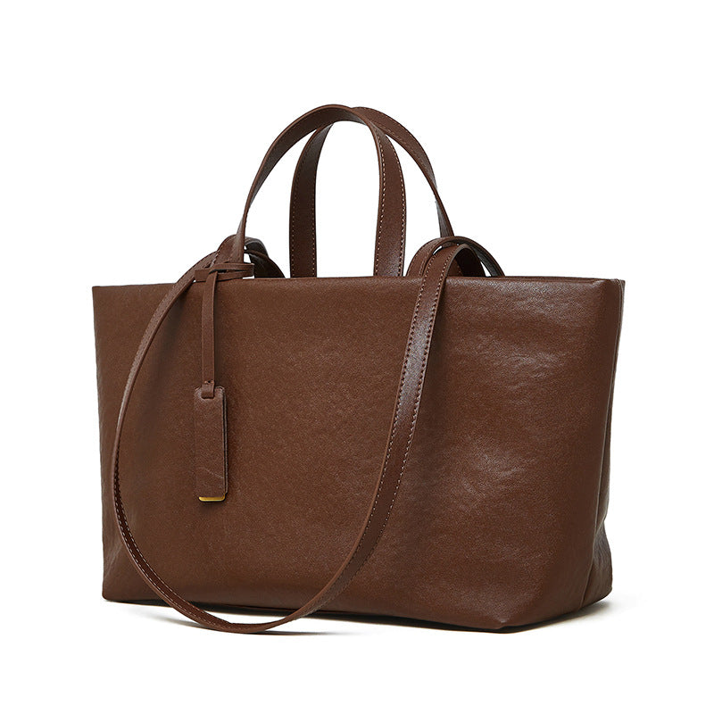 Brown cowhide leather tote bag with crossbody strap on white background