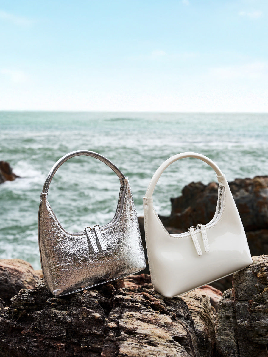 Silver and cream mini hobo bags styled on rocks by the sea