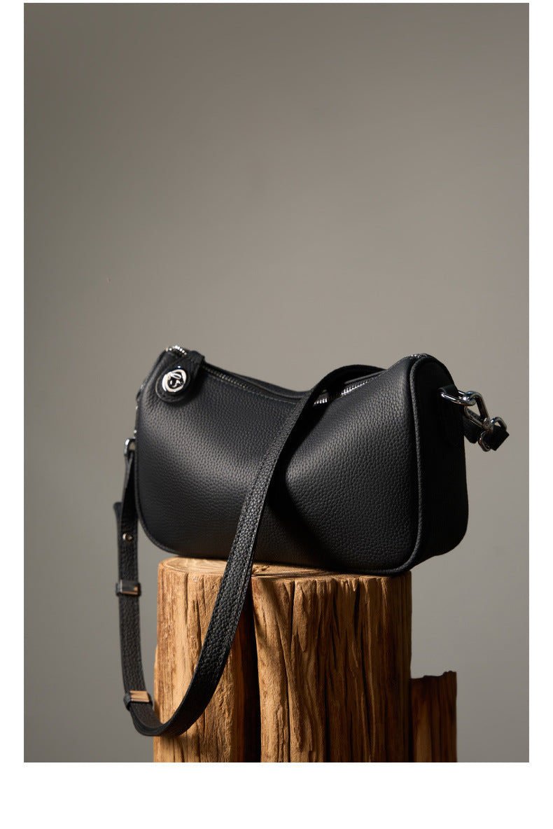 Black pebbled leather crossbody bag displayed on wooden block